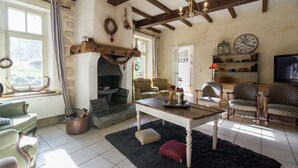 Una sala de estar acogedora con chimenea, vigas de madera, televisor y asientos cómodos.