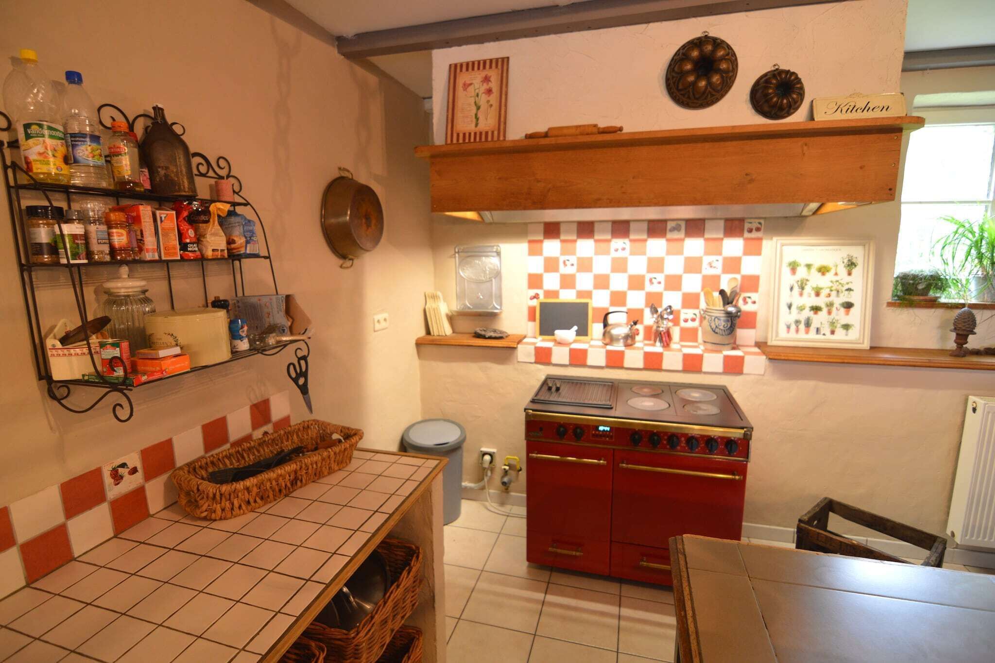 A kitchen with a red stove, checkered backsplash, and various kitchen items on shelves.