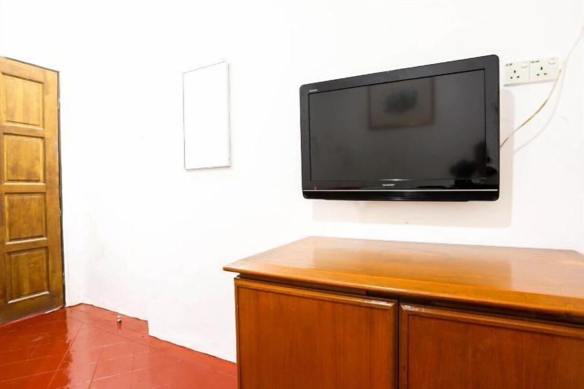 A room with a wooden cabinet, a whiteboard, and a mounted television on the wall.