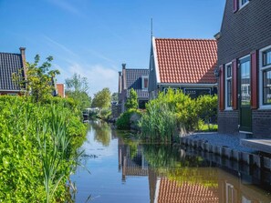 A canal with buildings on either side, a clear sky, and greenery along the water.