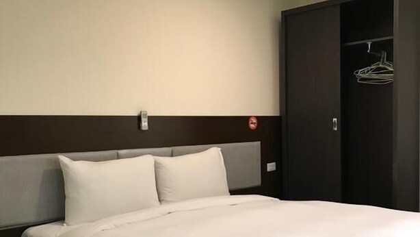 Un llit ben fet amb llençols blancs a una habitació d'hotel.