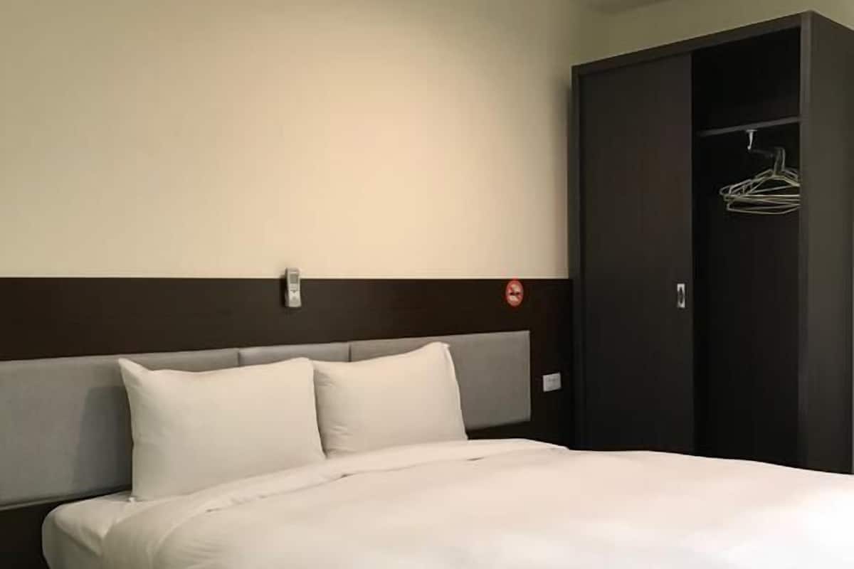 A neatly made bed with white linens in a hotel room.