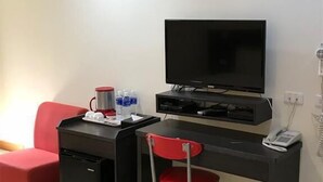 Habitació senzilla amb escriptori, cadira, televisió, cafetera i paperera.