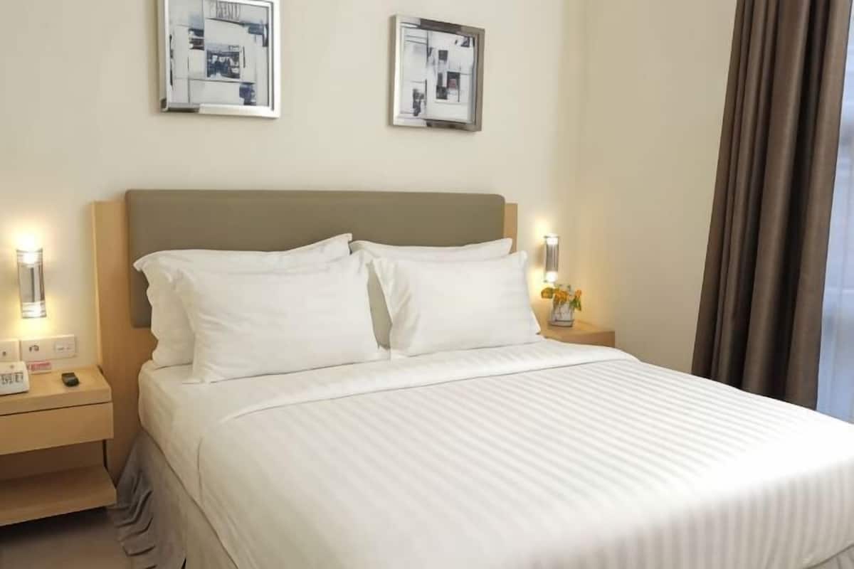 Una habitación de hotel con cama, mesitas de noche y lámparas fijadas a la pared.