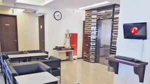 Un moderno vestíbulo de hotel con una recepción, un reloj y una zona de estar con mesas y sillas.