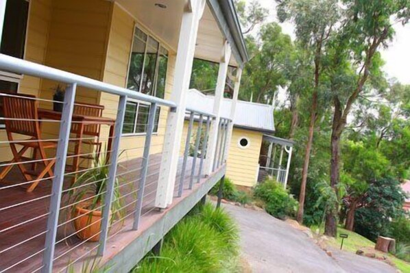 A two-story house with a balcony, a small garden, and a pathway leading to the house.