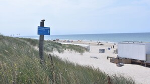 Una spiaggia con un cartello stradale, casette da spiaggia e una grande struttura bianca.