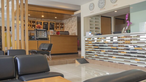 A modern reception area with a counter, seating, and a kitchen in the background.