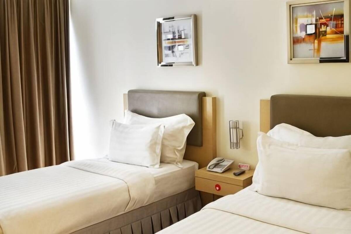 Ein Hotelzimmer mit zwei Betten, einem Nachttisch mit Telefon und einem Wandbild.