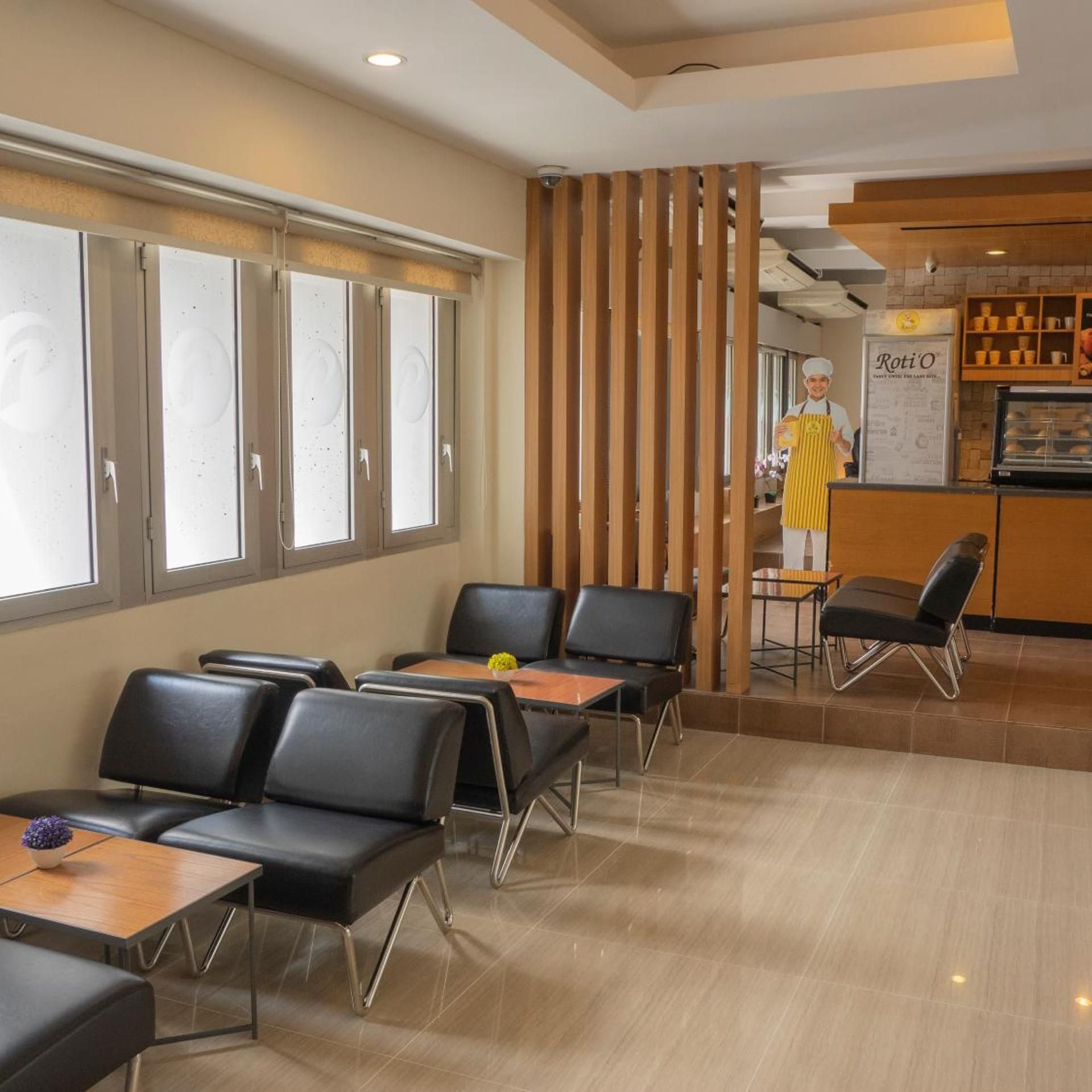 Un interior moderno con una zona de estar, una barra con una persona con delantal amarillo, y una cocina con una vitrina.