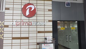 A building facade with a 'd'prima hotel' sign, a 'Terminal 1' sign, and a 'P' logo.