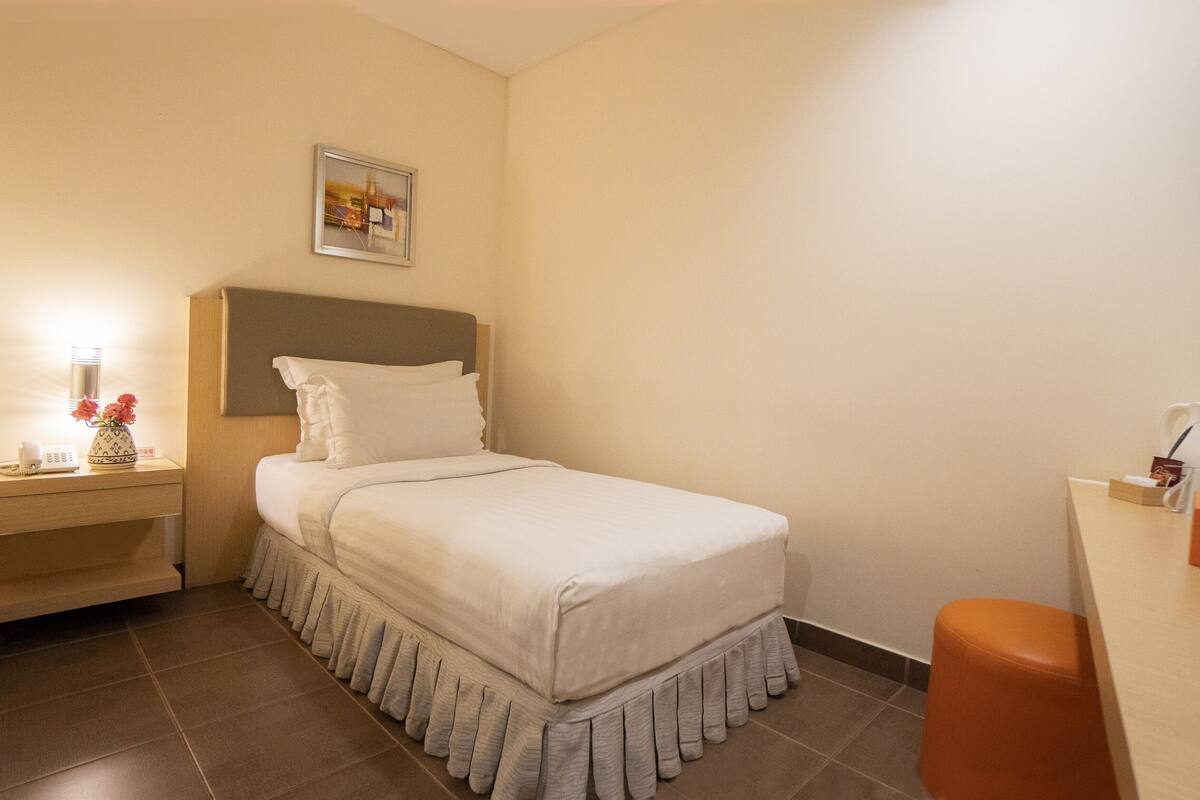 Ein Hotelzimmer mit Bett, Nachttisch und Schreibtisch mit Stuhl.