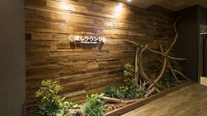Un mur en bois sur lequel est affiché un panneau indiquant « Espace de relaxation et de bien-être », ainsi qu’un petit jardin intérieur agrémenté de plantes et de branches.