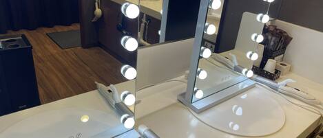 A bathroom vanity with a mirror, lights, and a hairdryer.
