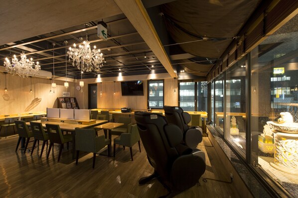 A modern lounge with wooden tables, comfortable seating, and a large window offering a view of the city.