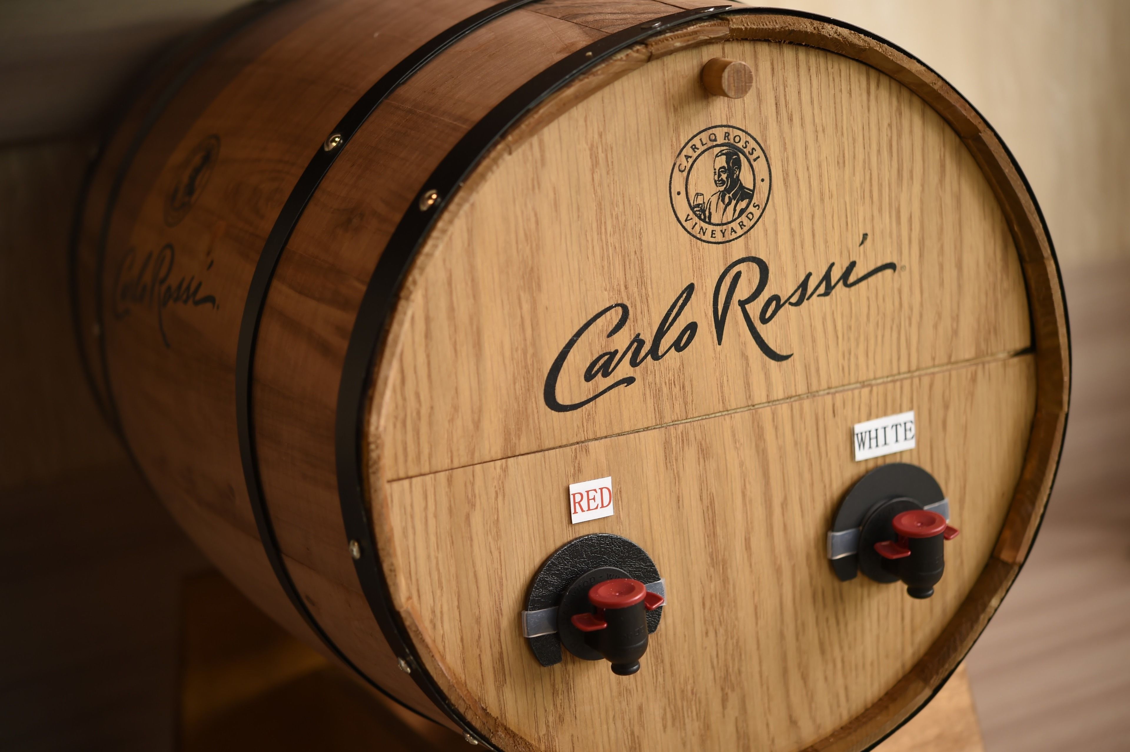 A wooden barrel with "Carlo Rossi" branding and two valves labeled "RED" and "WHITE".