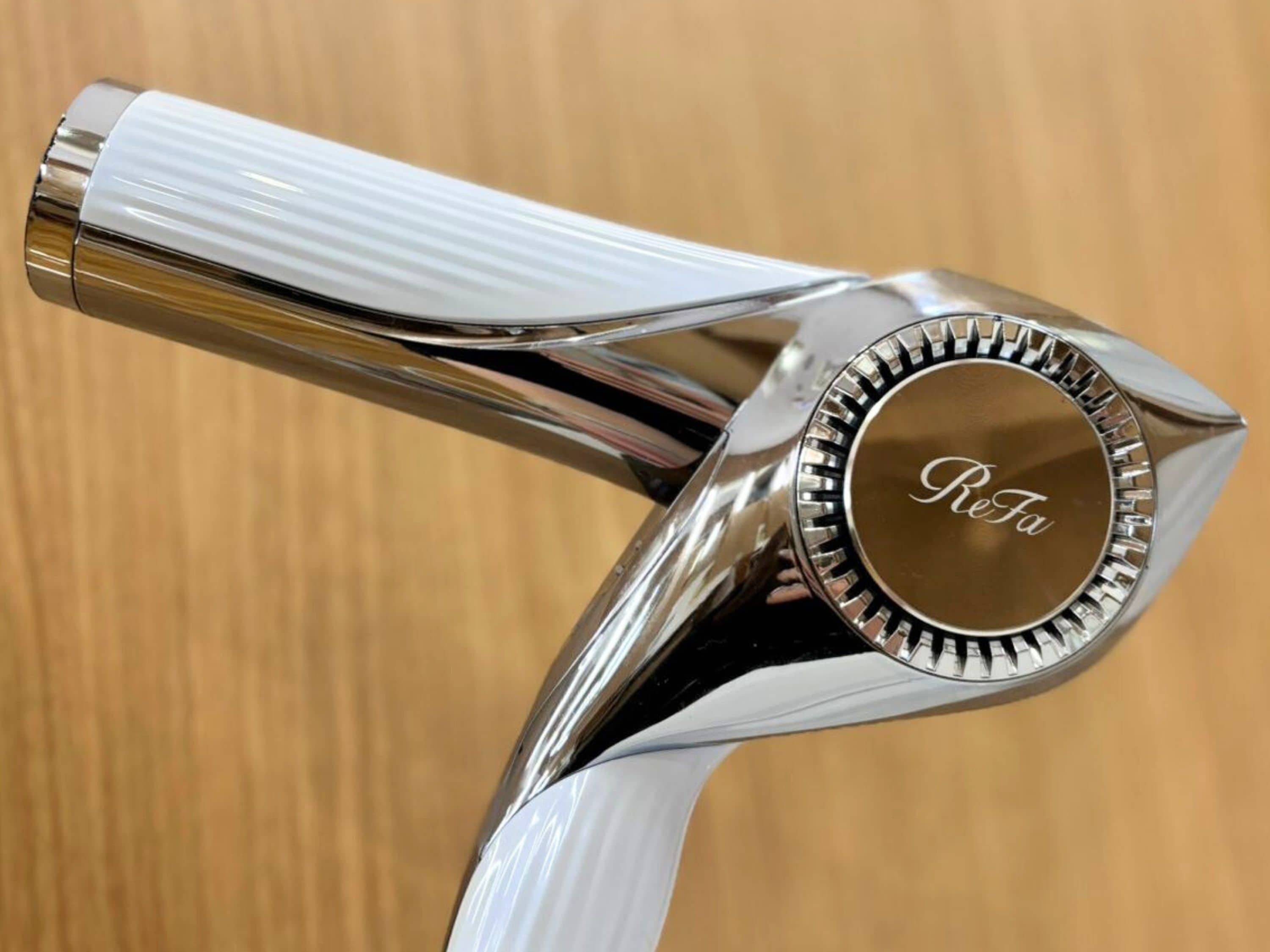 A metallic object with a reflective surface and the inscription "ReFa" on it.
