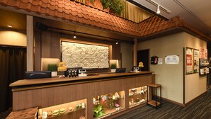 Un comptoir d’accueil surmonté d’un toit en tuiles, un grand mur décoratif et une présentation de produits locaux.