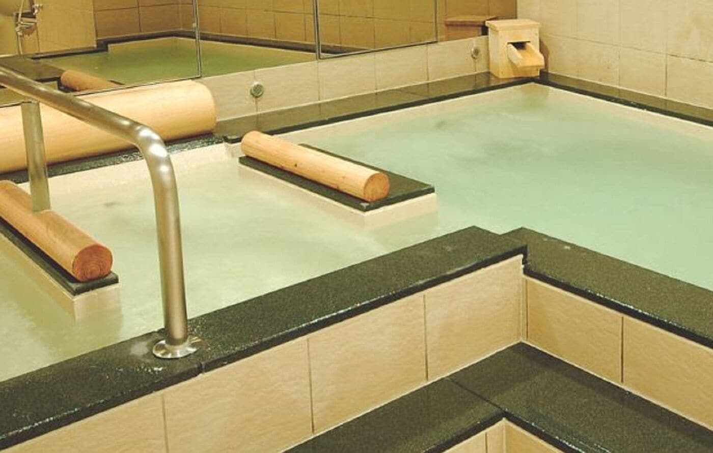 Un jacuzzi con escalones de madera y barandilla metálica.