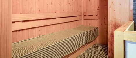 A sauna room with wooden walls, a bench, a clock, and a sign with instructions.