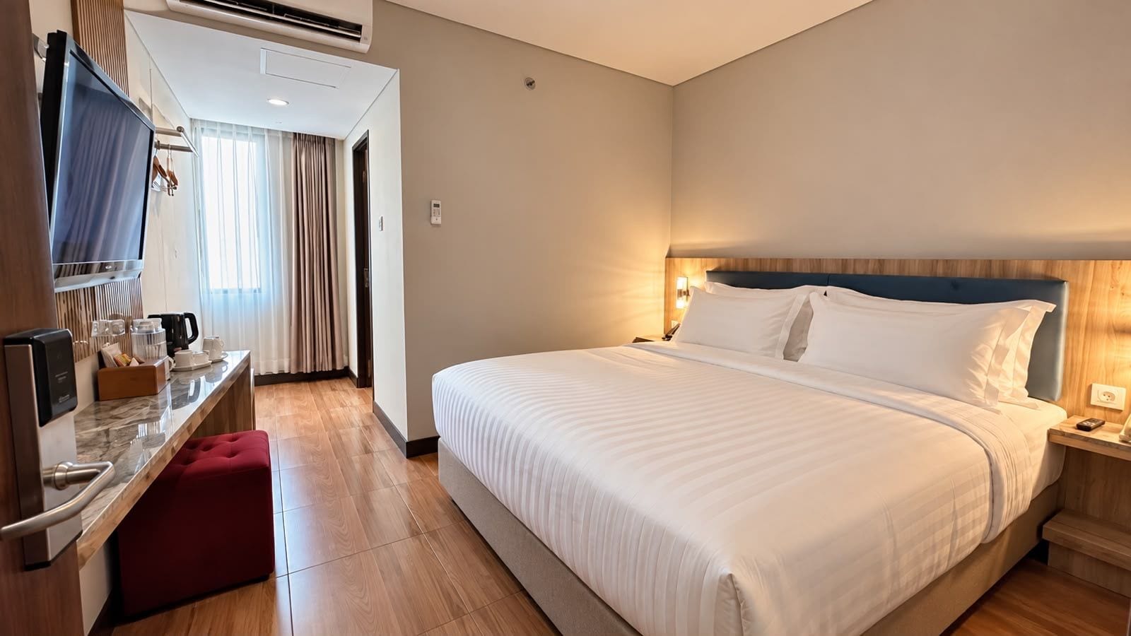 A hotel room with a bed, a desk, a television, and a coffee maker.