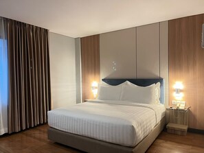 Una habitación de hotel con una cama grande, dos mesitas de noche con lámparas y una cortina en la ventana.