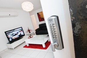 Uma sala de estar moderna com um sofá branco, um tapete vermelho, uma televisão de tela plana e uma fechadura digital.
