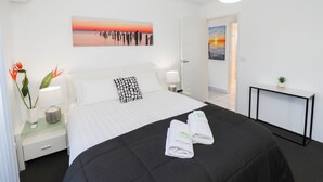 A hotel room with a bed, bedside tables, a desk, and artwork on the walls. - 112 Olive Apartments (Mildura)