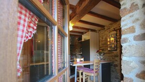 Una cucina accogliente con un tavolo di legno, sedie e un muro in pietra.