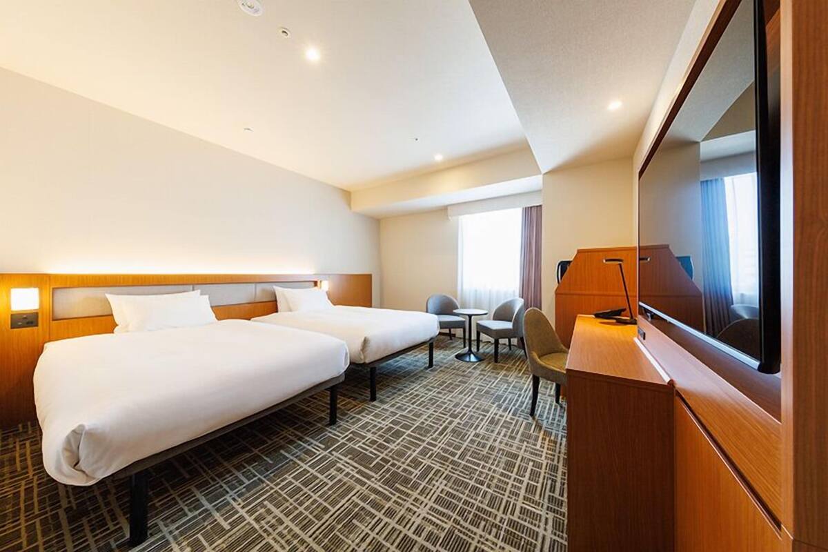 Une chambre d’hôtel avec deux lits, une télévision, un bureau et une petite table.