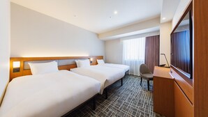 Une chambre d’hôtel avec deux lits, un bureau, une chaise, une télévision et une fenêtre avec des rideaux.