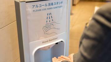Un dispensador de gel hidroalcohólico con instrucciones en varios idiomas, incluyendo inglés y japonés.
