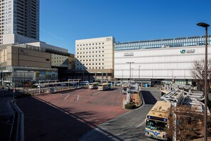 Ein Busbahnhof mit mehreren Bussen, ein großes Gebäude mit einer Beschilderung und ein Parkplatz.
