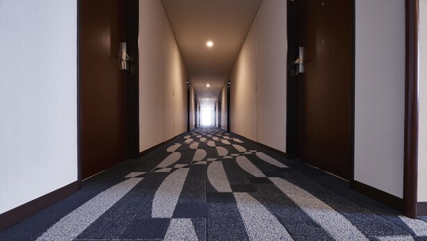 A long, narrow hotel corridor with a patterned carpet and wooden doors on either side. - JR East Hotel Mets Yokohama Tsurumi (Yokohama)