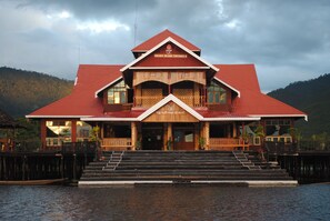 A large wooden building with a red roof, multiple balconies, and a staircase leading to the entrance. - Golden Island Cottages Thale-U Hotel (Nyaungshwe)