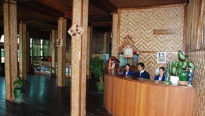 A reception area with a wooden reception desk, a clock, and a sign that reads "Reception". - Golden Island Cottages Thale-U Hotel (Nyaungshwe)