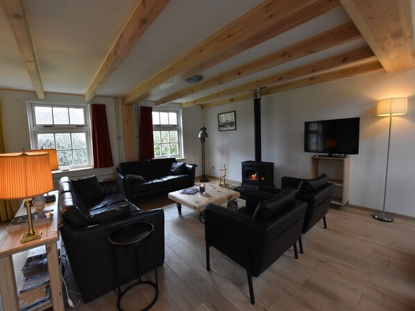 A cozy living room with a fireplace, sofas, a coffee table, and a TV.