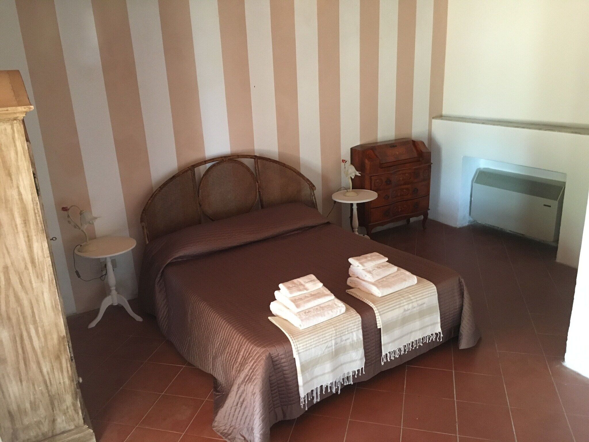 Un dormitorio con cama, cómoda, una mesita y radiador.