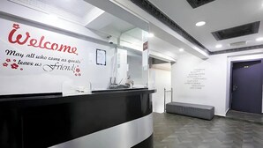 Un espace d’accueil doté d’un comptoir de réception noir et blanc, d’un panneau d’accueil et d’un mur affichant les services offerts aux clients.