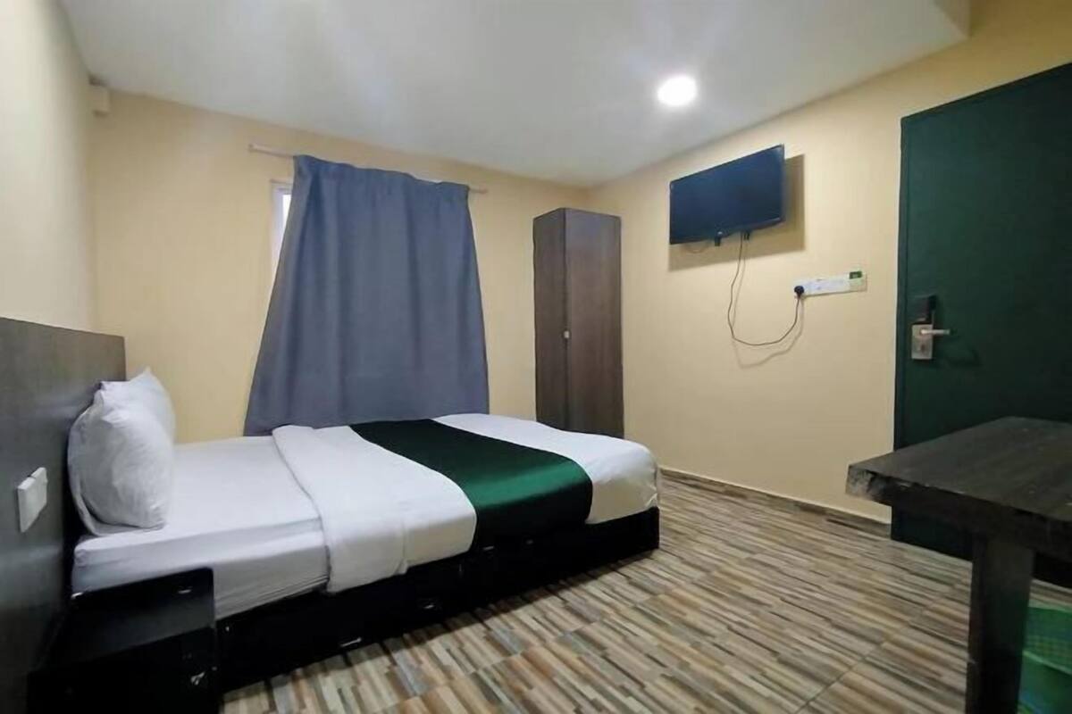A hotel room with a bed, a desk, a television, and a door.