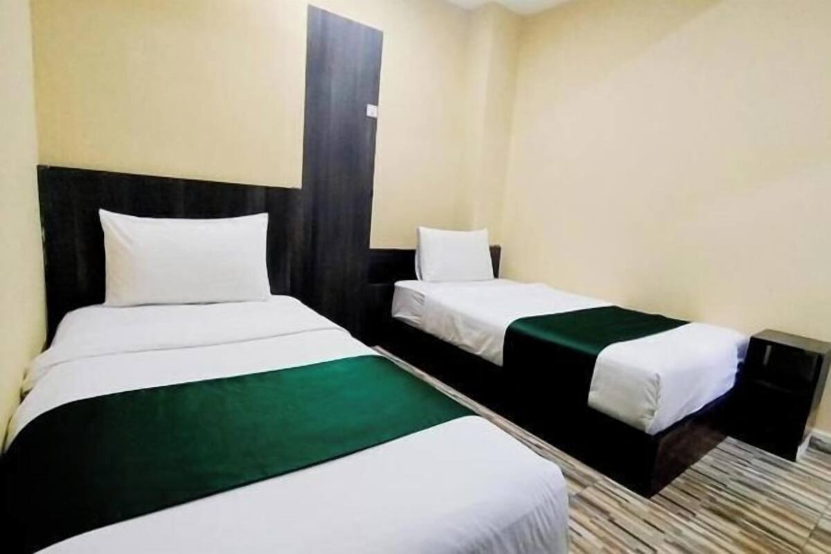 A hotel room with two beds, a dark headboard, and a carpeted floor.