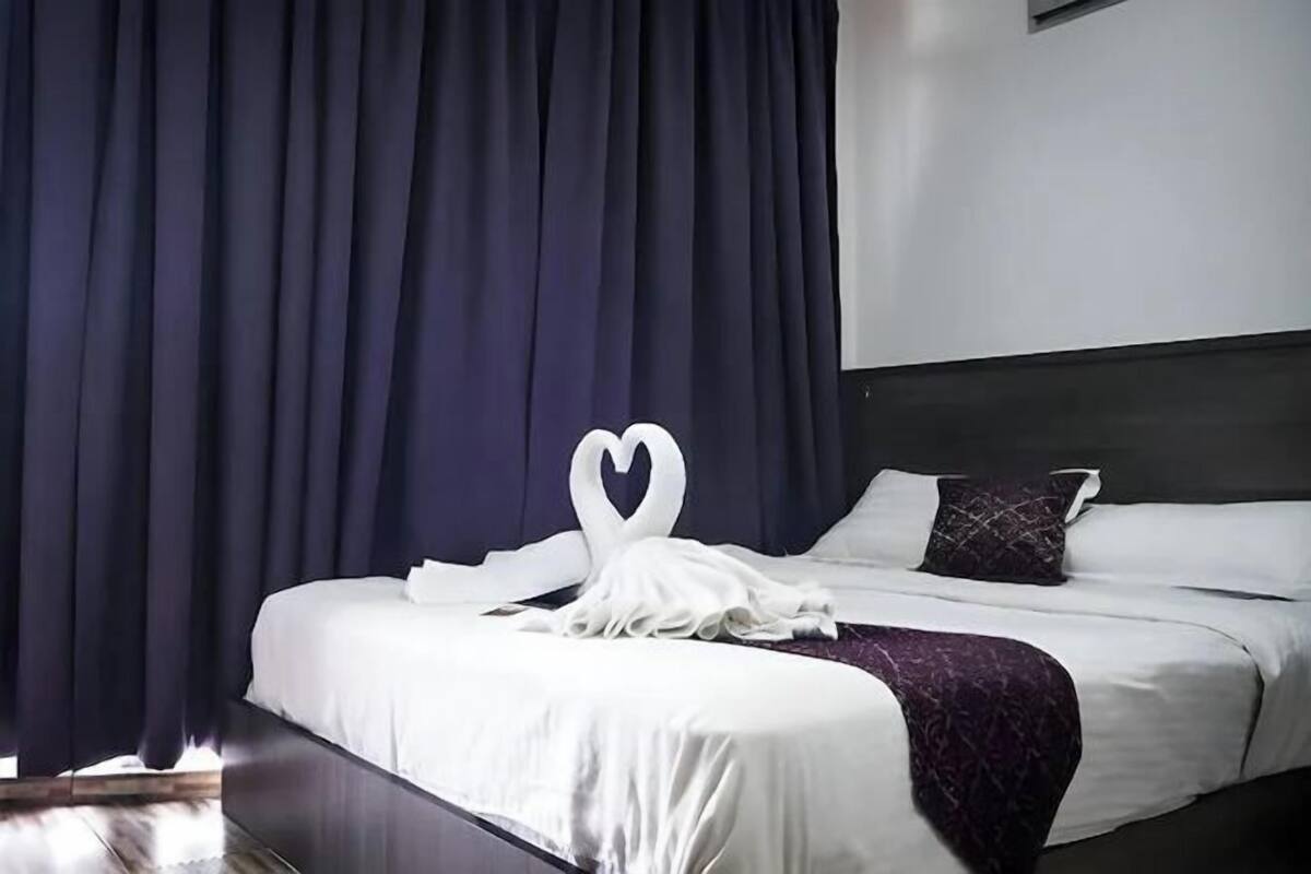 A neatly made bed with white linens and a purple throw blanket.
