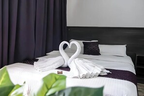 Una habitación de hotel con una cama bien hecha, un cabecero y un ventanal grande.