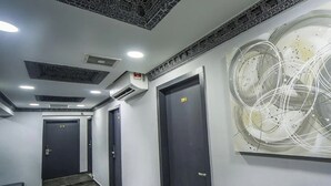 Un couloir avec des portes sombres, un plafond orné de motifs et une œuvre d’art abstraite accrochée au mur.