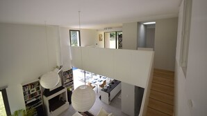 A modern interior with a high ceiling, a fireplace, bookshelves, a dining area, and a kitchen. - Holiday Home in Boissières with Private Pool (Boissieres)