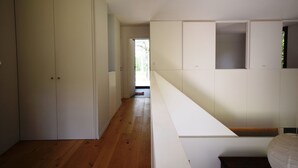 A modern, minimalist room with a wooden floor, white walls, and built-in storage units. - Holiday Home in Boissières with Private Pool (Boissieres)