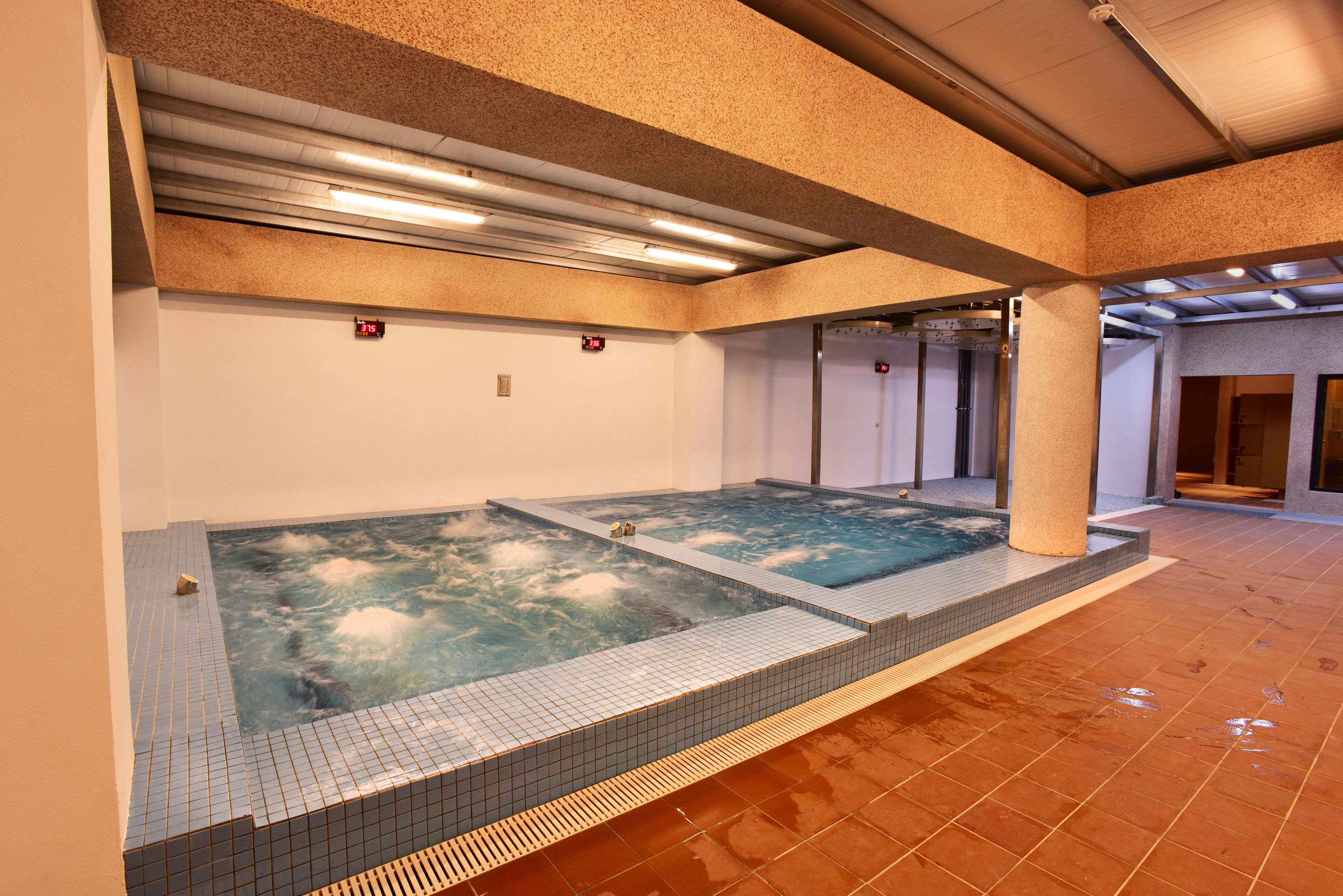 A spa area with two hot tubs and a tiled floor.