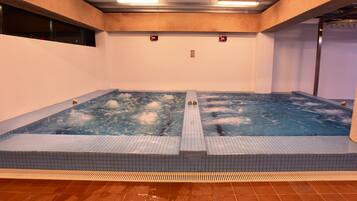 Una amplia piscina interior con solárium de azulejos y superficie de agua cristalina.