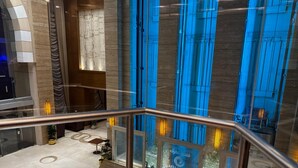 A hotel lobby with a marble floor, a glass railing, and a view of the interior through large windows. - Afraa Hotel (Makkah)