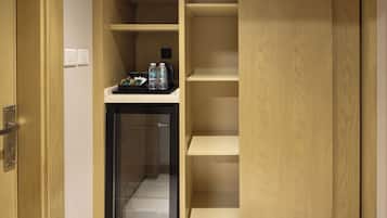 Habitación de hotel con minibar, refrigerador pequeño y armario de madera.